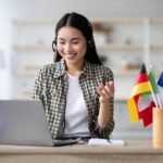 Happy asian lady using laptop and headset, learning foreign language